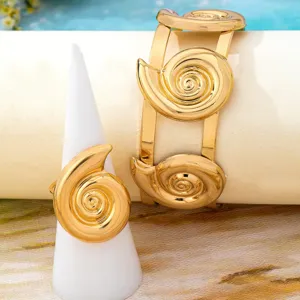 Primer plano del anillo concha geométrico dorado y el brazalete ancho de estilo playero.