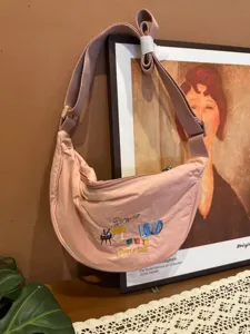 Pink nylon crescent crossbody bag detail, cute music character embroidery and adjustable strap.