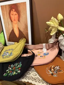 Detailed view of embroidered crescent crossbody bags showcasing colorful floral and animal patterns.