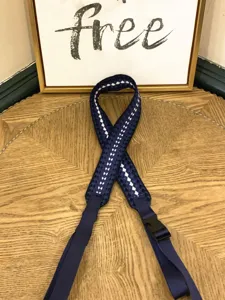 Close-up of a navy blue woven nylon bag strap with white pattern and adjustable buckle.