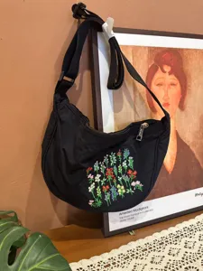 Black nylon dumpling crossbody bag with colorful floral embroidery, casual shoulder bag.