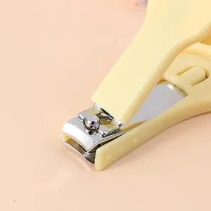 Nahaufnahme des gelben Nagelknippers mit Spritzschutz, kompaktes Maniküre-Werkzeug für Alltag.