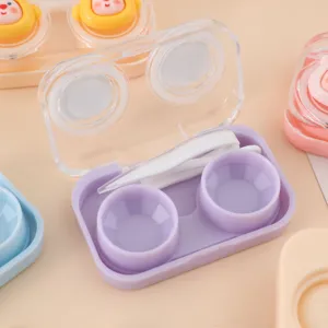 Primer plano detalle de estuche de lentillas portátil con tapa transparente y pinzas lila.