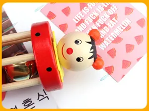 Cute wooden baby rattle toy featuring a cartoon wooden puppet head and pleasant bell for infants.