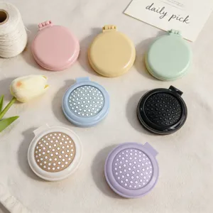 Colorful portable folding hair brush detail shot showing cute pastel colors and compact mirror design.