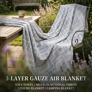 Outdoor detail view of soft grey geometric 3-layer gauze throw blanket in cozy garden setting.