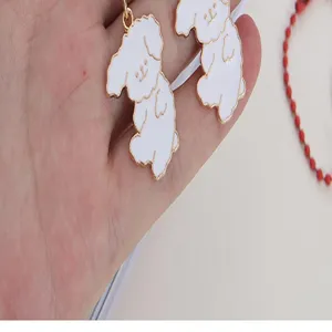 Close-up detail of cute white cartoon puppy metal keychain pendant and bag accessory.