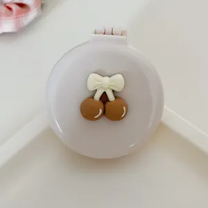 Compact foldable air cushion hair brush with mirror, cute cherry decor, portable mini styling tool.