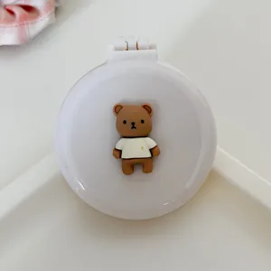 Compact folding air cushion hair brush with built-in mirror and cute brown bear detail.