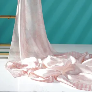 Vista dettagliata della sciarpa di seta rosa con stampa, drappeggio morbido ed elegante.