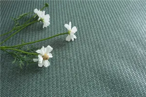 Dettaglio texture tappeto in rattan seta di ghiaccio verde con superficie tessuta e fiore.