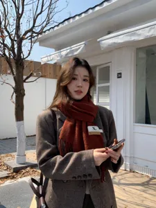 Detailed view of women's autumn winter tassel scarf and herringbone blazer outdoor street style