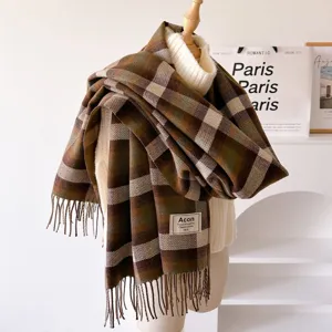 Detailed view of retro brown and green plaid fringe scarf shawl displayed on white turtleneck sweater.