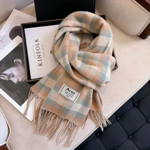 Detailed close-up view of a cozy plaid tassel scarf with warm beige and green tones.