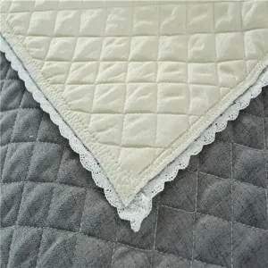 Quilted sofa cushion detail, diamond pattern texture, white lace edge home textile fabric.