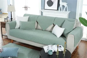 Green quilted sofa cover detail view, showing soft fabric texture and neat home decor setup.