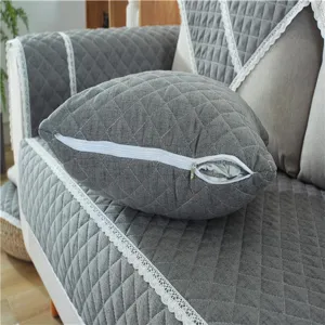 Gray quilted sofa cushion detail, fabric pillowcase with white lace trim and zipper.
