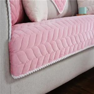 Detailaufnahme des dicken rosa Plüsch-Sofakissens mit gesteppter Textur und weißem Pomponrand.