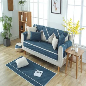 Quilted blue sofa cover set with white lace trim and matching rug for living room decor.