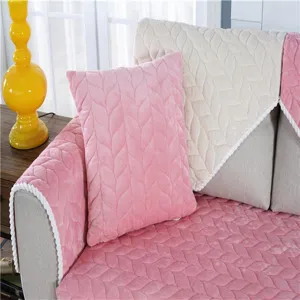 Nahaufnahme von plüschigen Sofakissen und Bezügen im Blattmuster in Rosa und Beige.