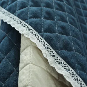 Close-up detail of quilted blue sofa cover fabric with elegant white lace trim and anti-slip.