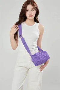 Detail view of purple knit crossbody bag worn by model, showing textured bubble design and strap.
