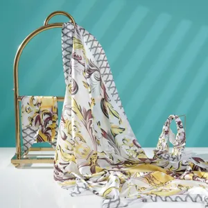 Detailed view of luxury baroque printed silk scarf with golden display stand and matching headband.