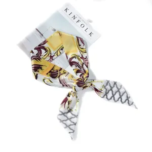 Detail shot of a luxury baroque printed silk twilly scarf in yellow and grey for women.