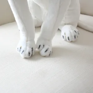 Close-up detail of white realistic simulation plush toy paws with soft fabric background.