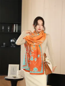 Elegant orange floral patterned winter scarf detail showcasing soft cashmere-feel fabric and colors.