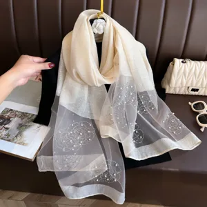 Vue détaillée du foulard en soie beige transparent avec de superbes perles florales.