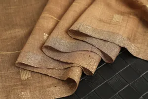 Close-up detail of luxury golden shimmering grid scarf fabric, elegant texture and delicate folds.