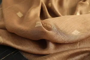 Close-up detail shot of the brown silk wool scarf showing delicate golden thread embroidery texture.
