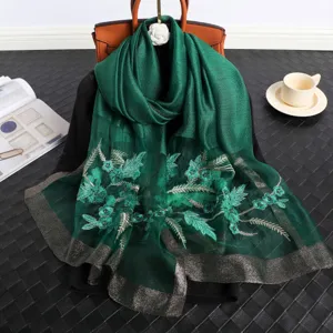 Elegante sciarpa in seta verde ricamata con motivi floreali e bordo metallico dettaglio.