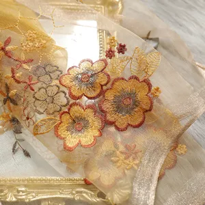 Exquisite floral embroidery detail on sheer silk blend scarf, elegant close-up view.
