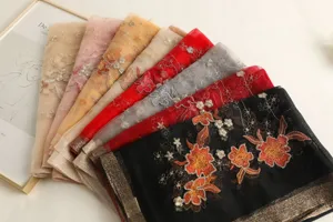 Ansicht bunter bestickter Seidenschals mit filigranen Blumenmustern und edlem metallischem Rand.