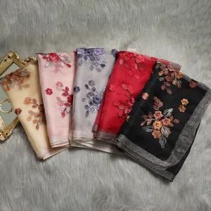 Silk embroidered scarf detail with vibrant floral patterns and metallic trim in multiple colors.