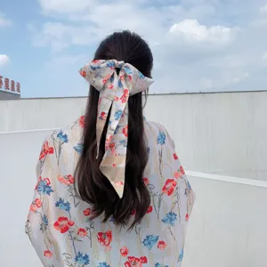 Close-up detail of the elegant floral print bow hair accessory and matching summer shirt.