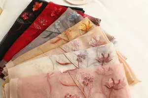 Close up detail of lightweight sheer embroidered floral scarves with delicate lotus patterns.