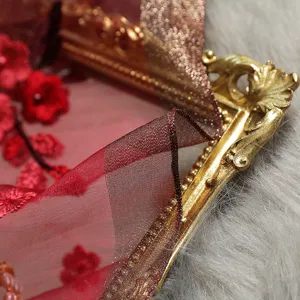 Close-up detail of maroon sheer silk scarf with red floral embroidery and pearl accents.