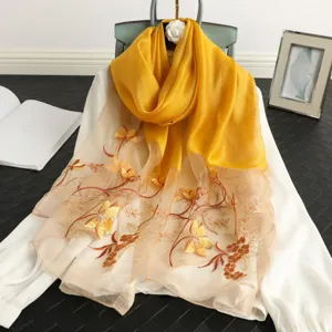 Yellow silk wool embroidered scarf detail showing intricate floral patterns and smooth fabric texture.