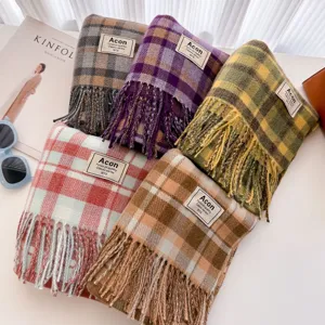 Detailed view of colorful plaid fringe scarves, soft winter shawl texture close up display.