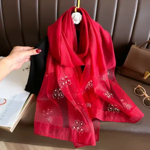 Exquisite detail of red polyester long scarf featuring elegant rhinestone and pearl flower patterns.