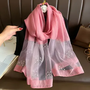 Details of pink long scarf featuring delicate pearl and rhinestone floral embellishments.