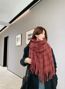Detailed view of the cozy red plaid winter scarf with chic fringe, offering warmth and style.