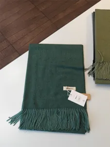 Dunkelgrüner einfarbiger Kaschmirimitat-Schal mit Fransen, Detailansicht von Textur und Etikett.