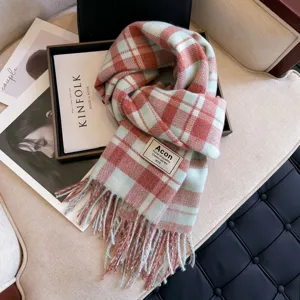 Detailed view of the cozy pink and blue plaid winter scarf with elegant fringe and soft texture.