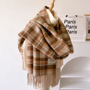 Detailed view of a retro plaid fringed scarf with woven brand label, soft autumn winter texture.