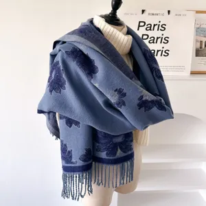 Detail view of blue floral jacquard winter scarf with long tassels, cozy textured shawl.