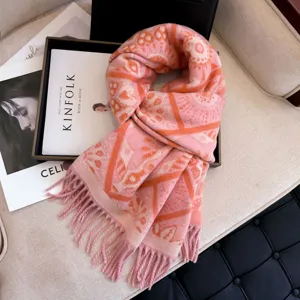 Detailed view of cozy pink winter warm geometric scarf with chic fringe on sofa.